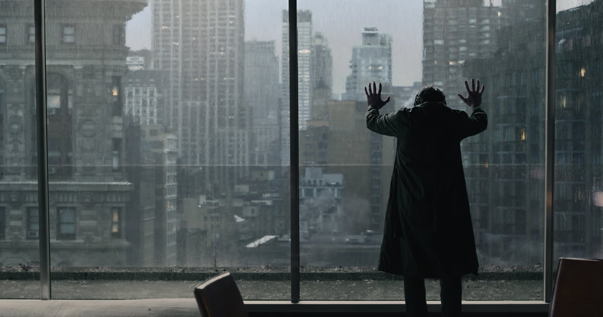 A still of Doctor Strange with his hands against tall glass windows looking out over a city